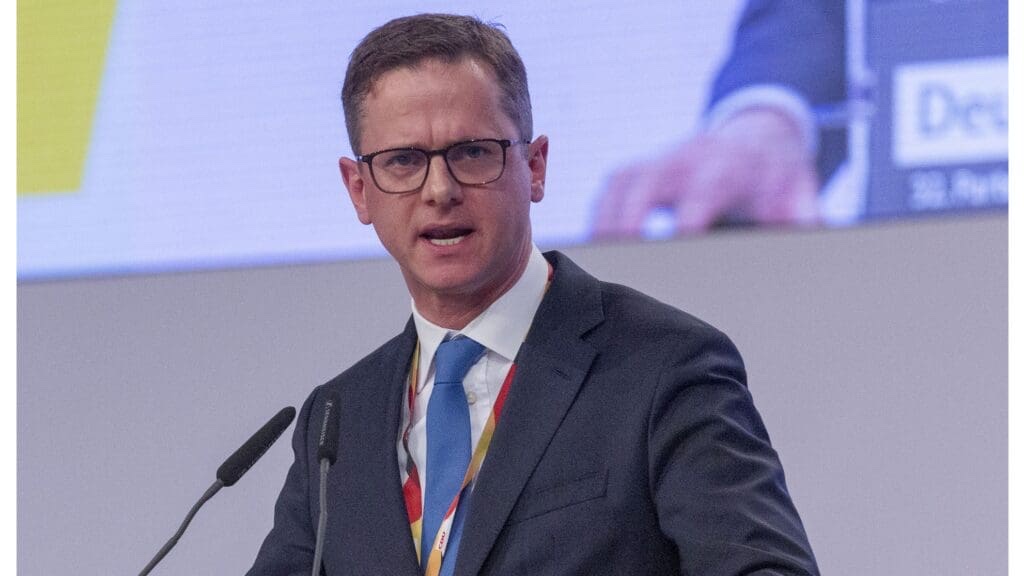 Carsten Linnemann speaking at the lectern of a CDU federal party congress, wearing a delegate lanyard
