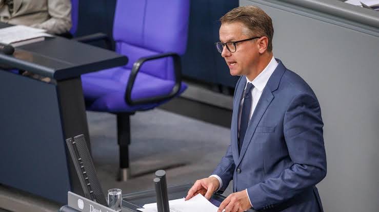 Carsten Linnemann in a grey-blue suit speaking at the lectern of the German Bundestag